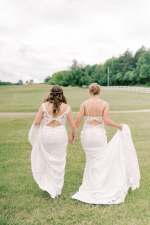 Bride and bride holding hands walking away summer wedding. Classic and film-inspired wedding photography in Madison, Wisconsin.
