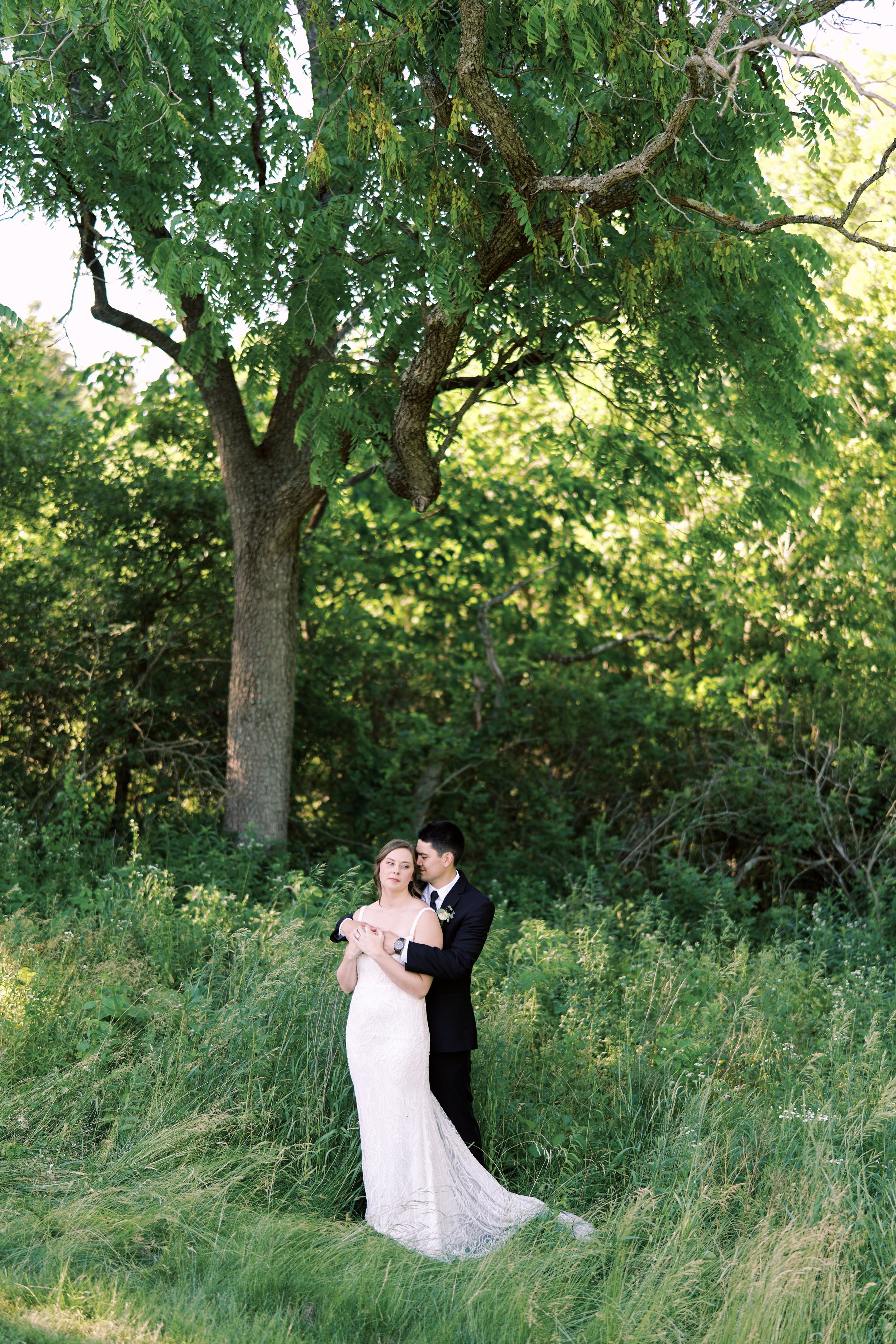 Classic and film-inspired wedding photography in Madison, Wisconsin. Bride and Groom standing in green summer forest The Eloise Mount Horeb