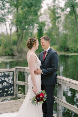 Bride and groom outdoor portrait candid near pond with willow tree. Classic and film-inspired wedding photography in Madison, Wisconsin.