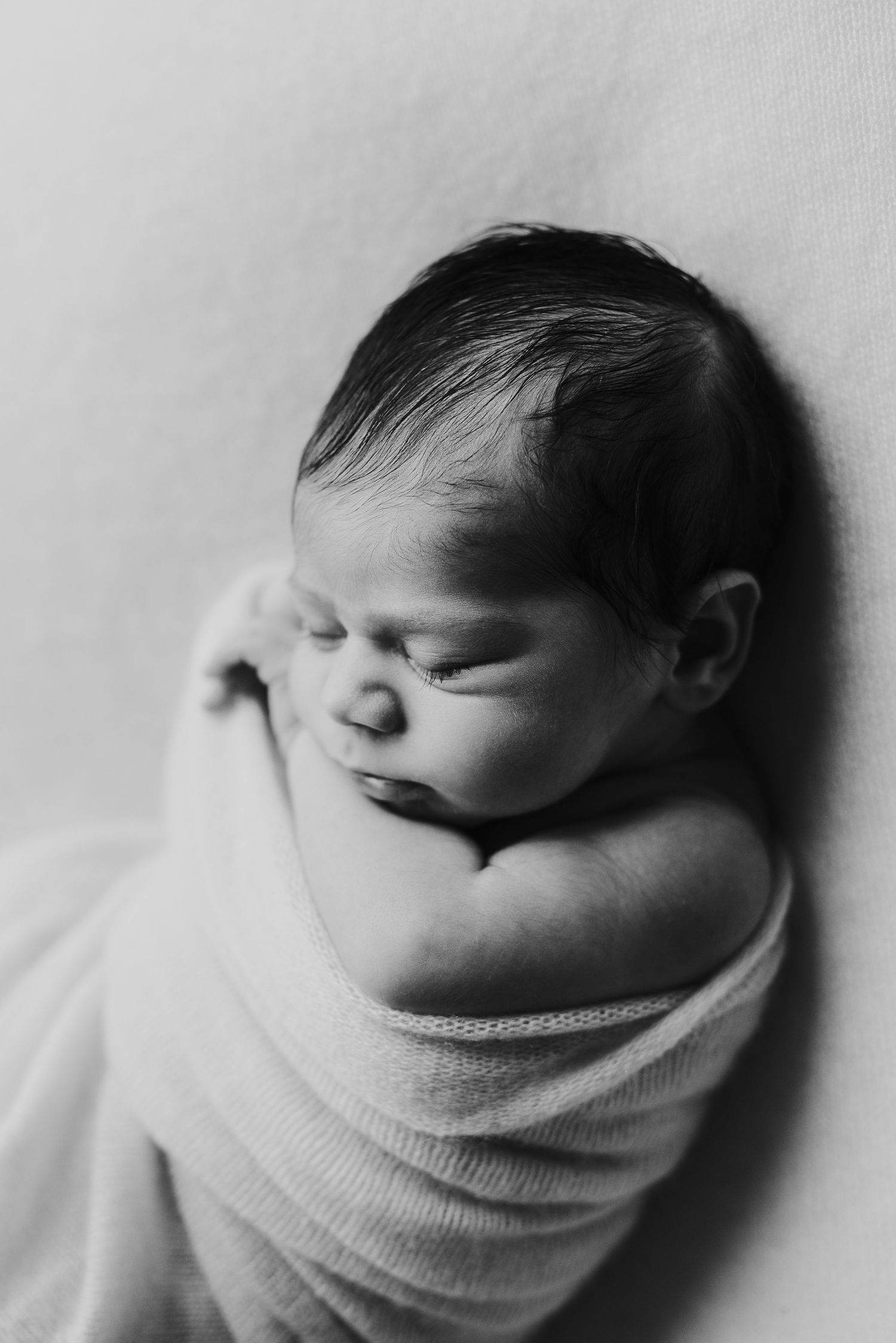 Black and white photo of newborn baby wrapped in blanket