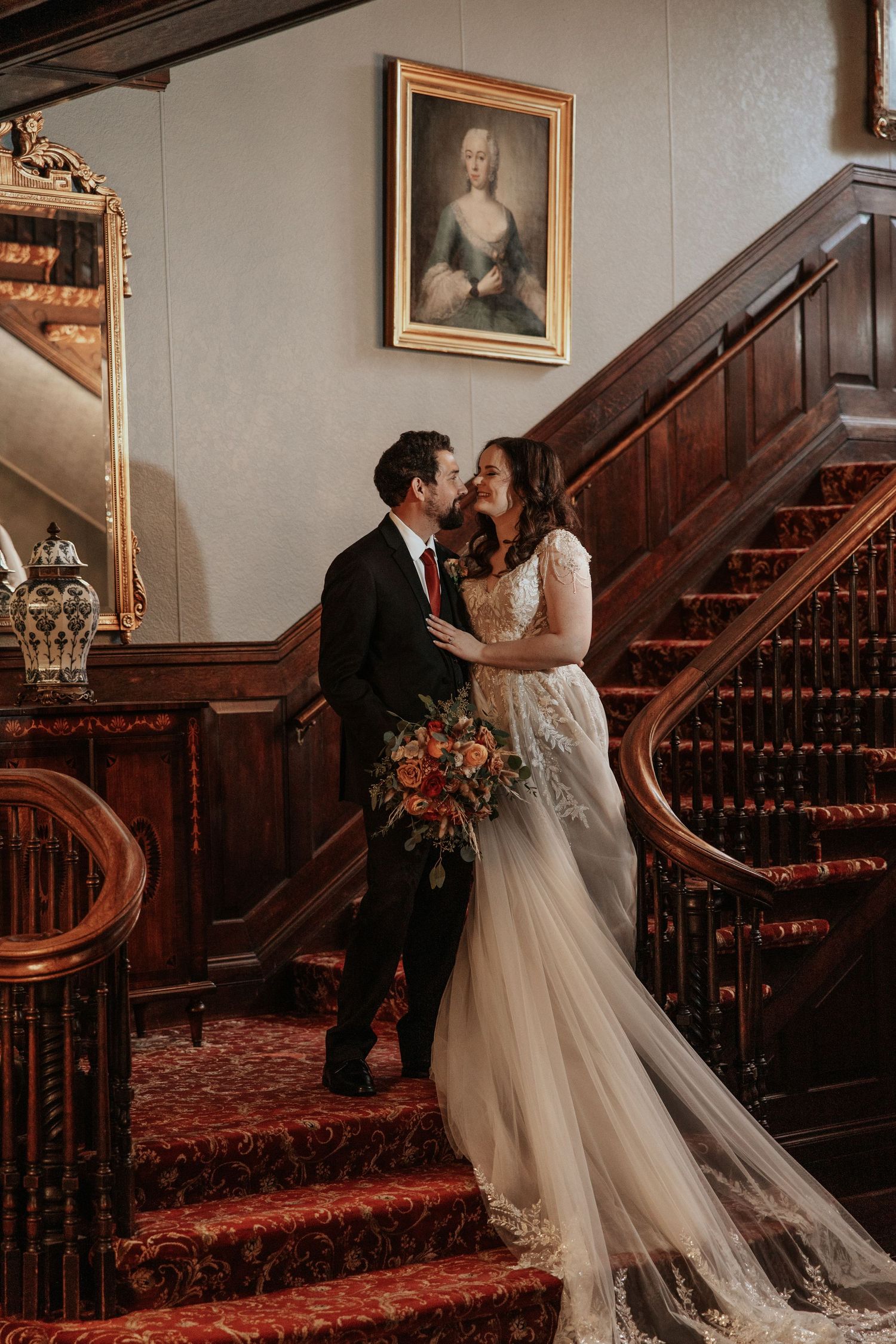 A romantic wedding portrait on an elegant wooden staircase with vintage decor.