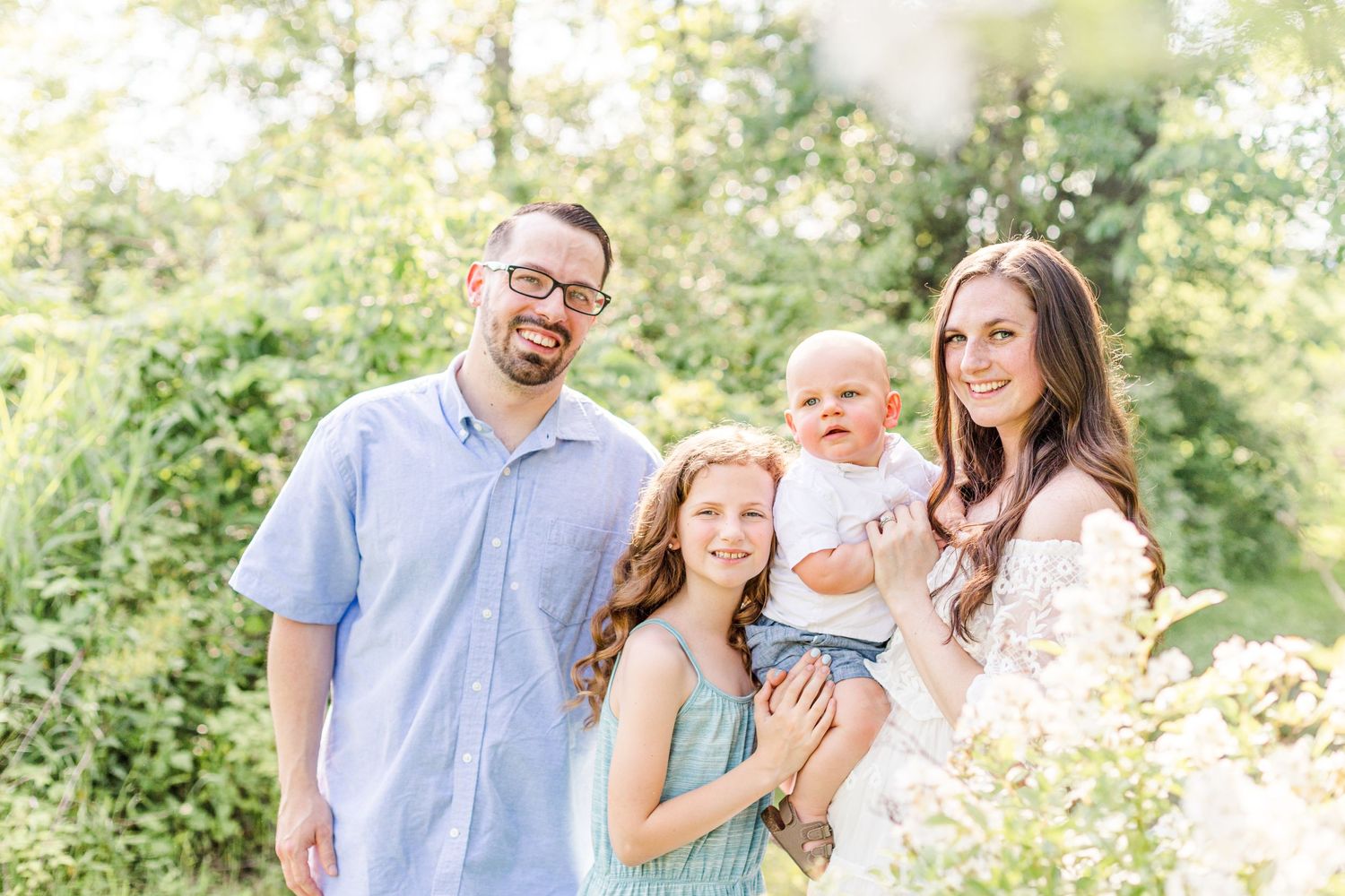 Family smiling during a summer photo session in the woods  at golden hour in New Paltz, NY