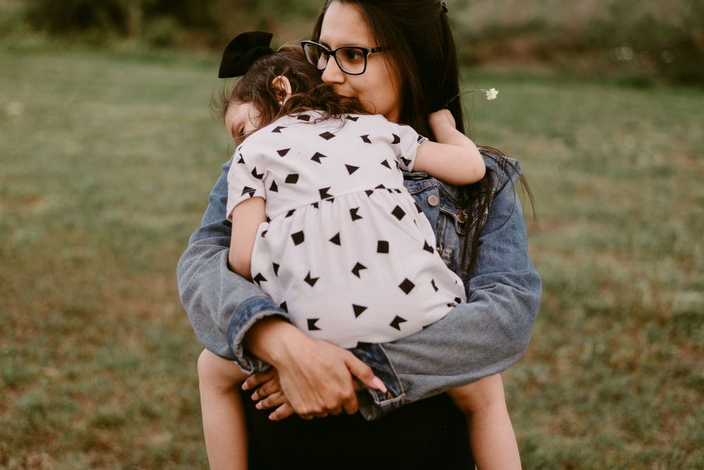 Tender embrace in a field wearing denim jacket and black dress.