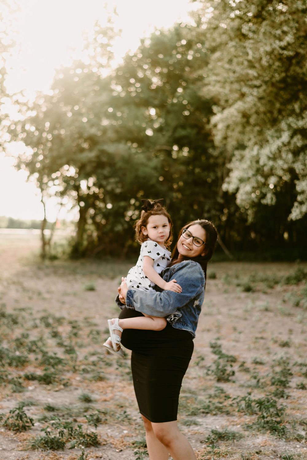 Sweet outdoor moment captured in golden sunlight with flowering trees in background.