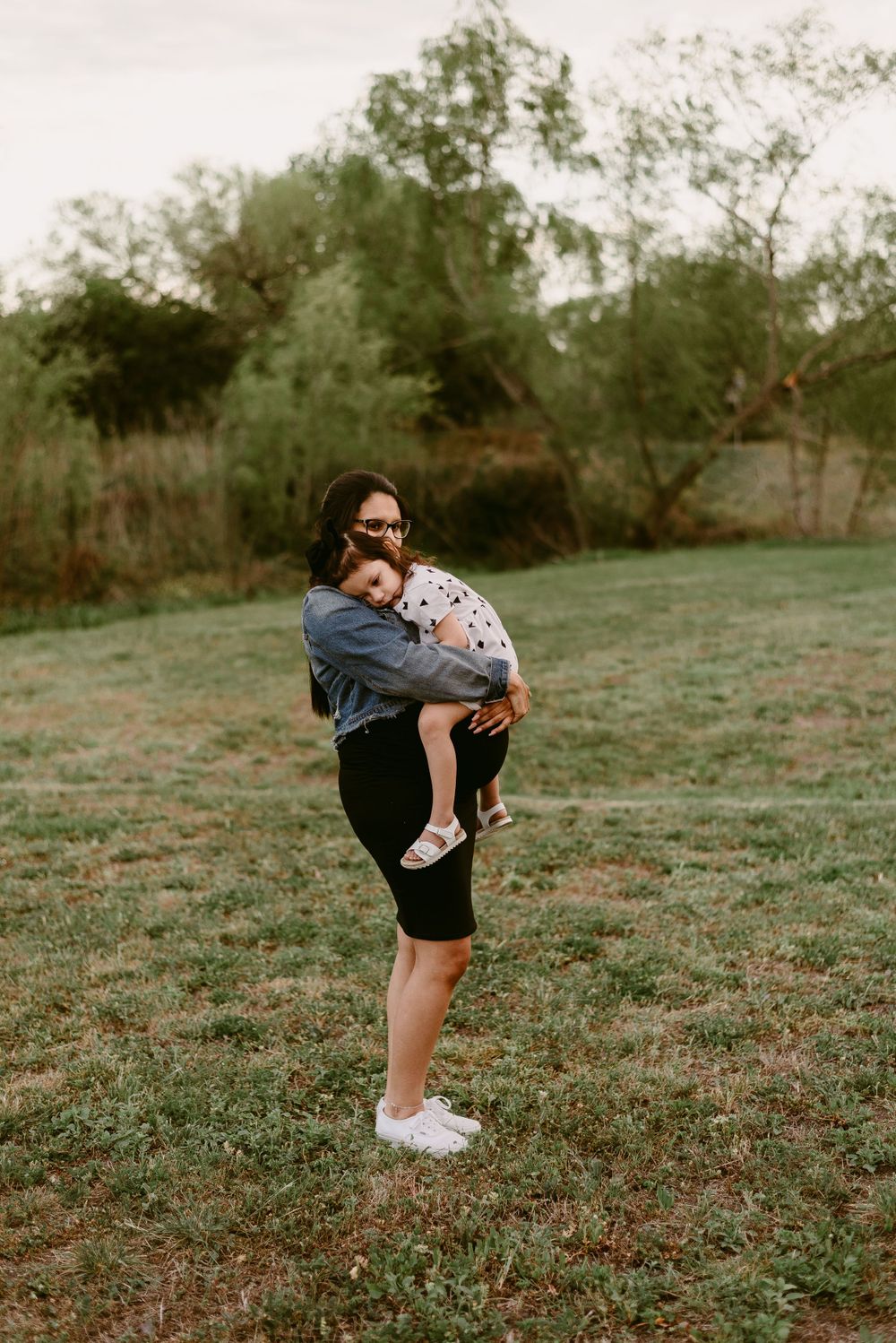 Casual outdoor portrait in a denim jacket and black skirt against flowering trees.