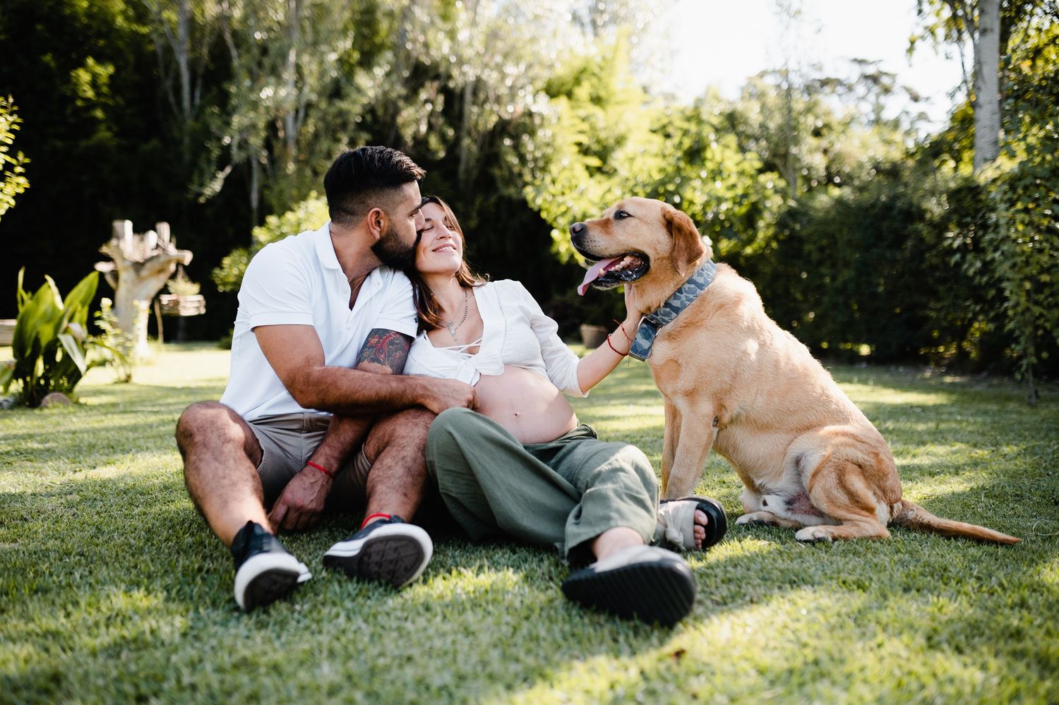 A couple and their dog enjoy a sunny afternoon together on the lawn.