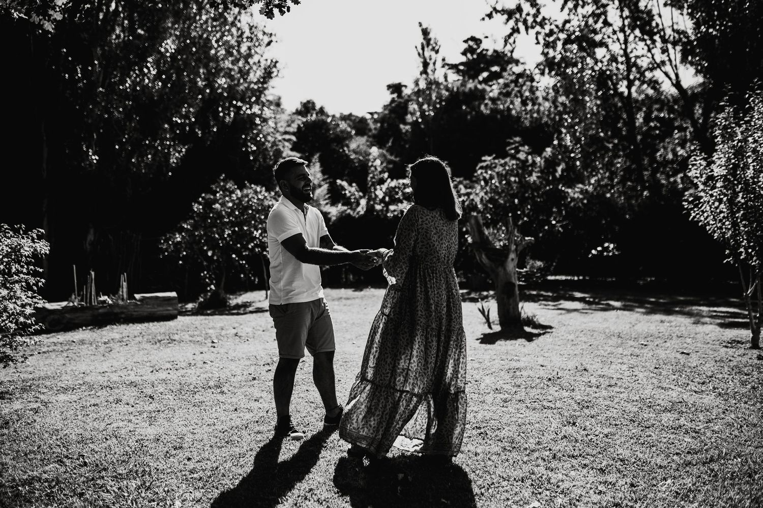 Black and white photo capturing a tender moment between a couple in a park.