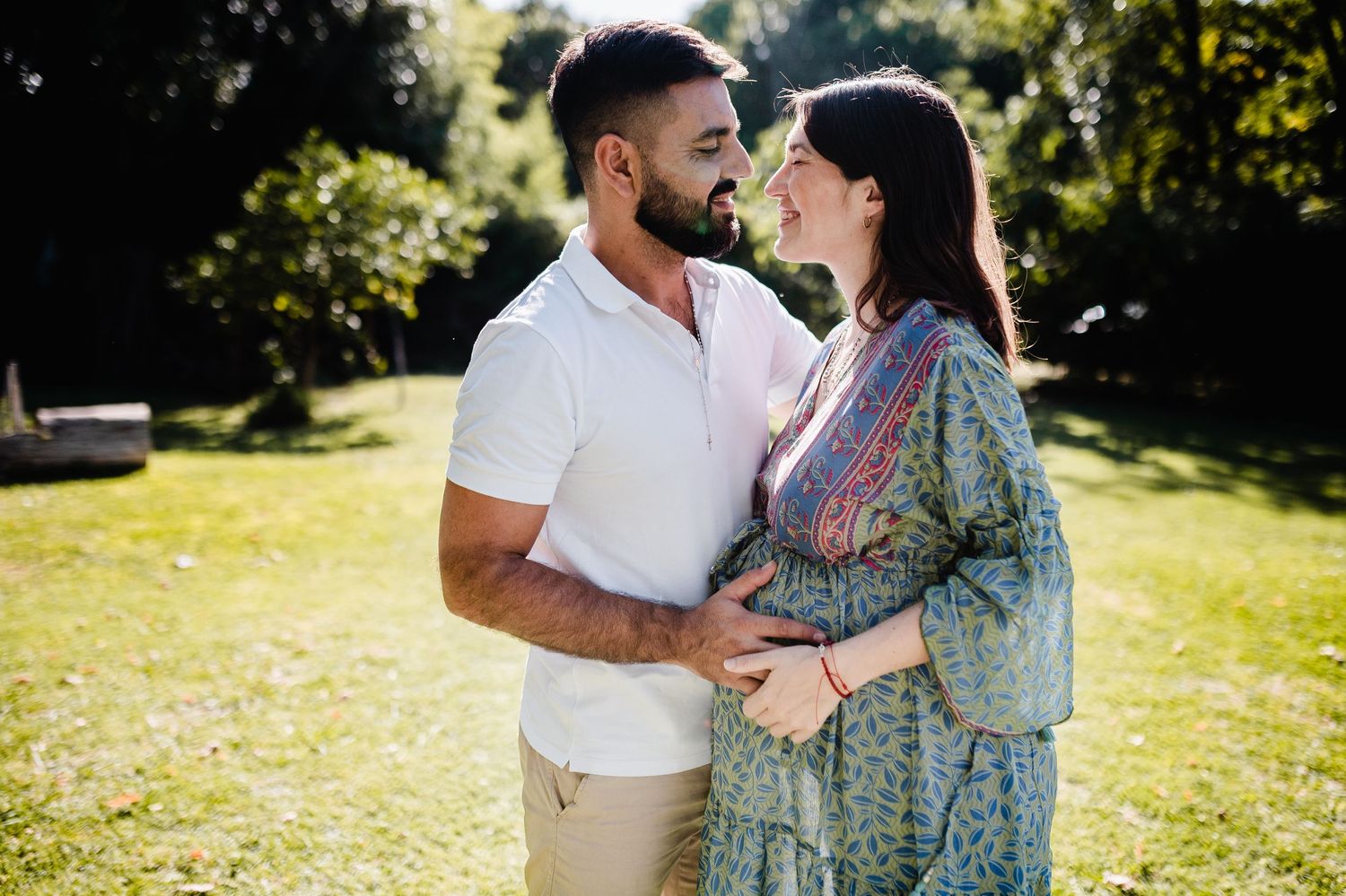 A romantic outdoor photoshoot in a park with sunlit foliage in the background.