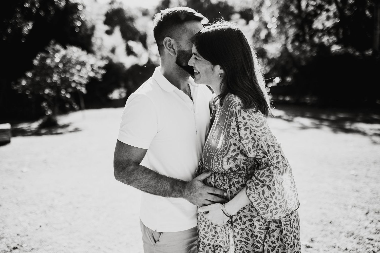 A couple embraces during an outdoor photo session with soft lighting.