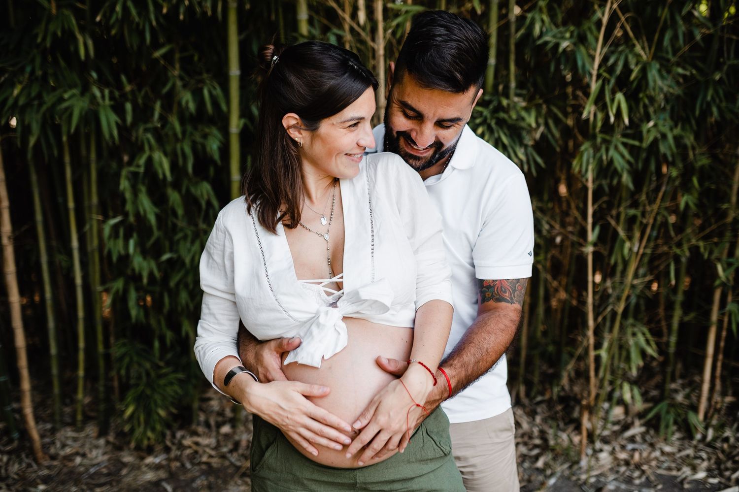 A couple in white outfits sharing intimate moments in a bamboo garden setting.