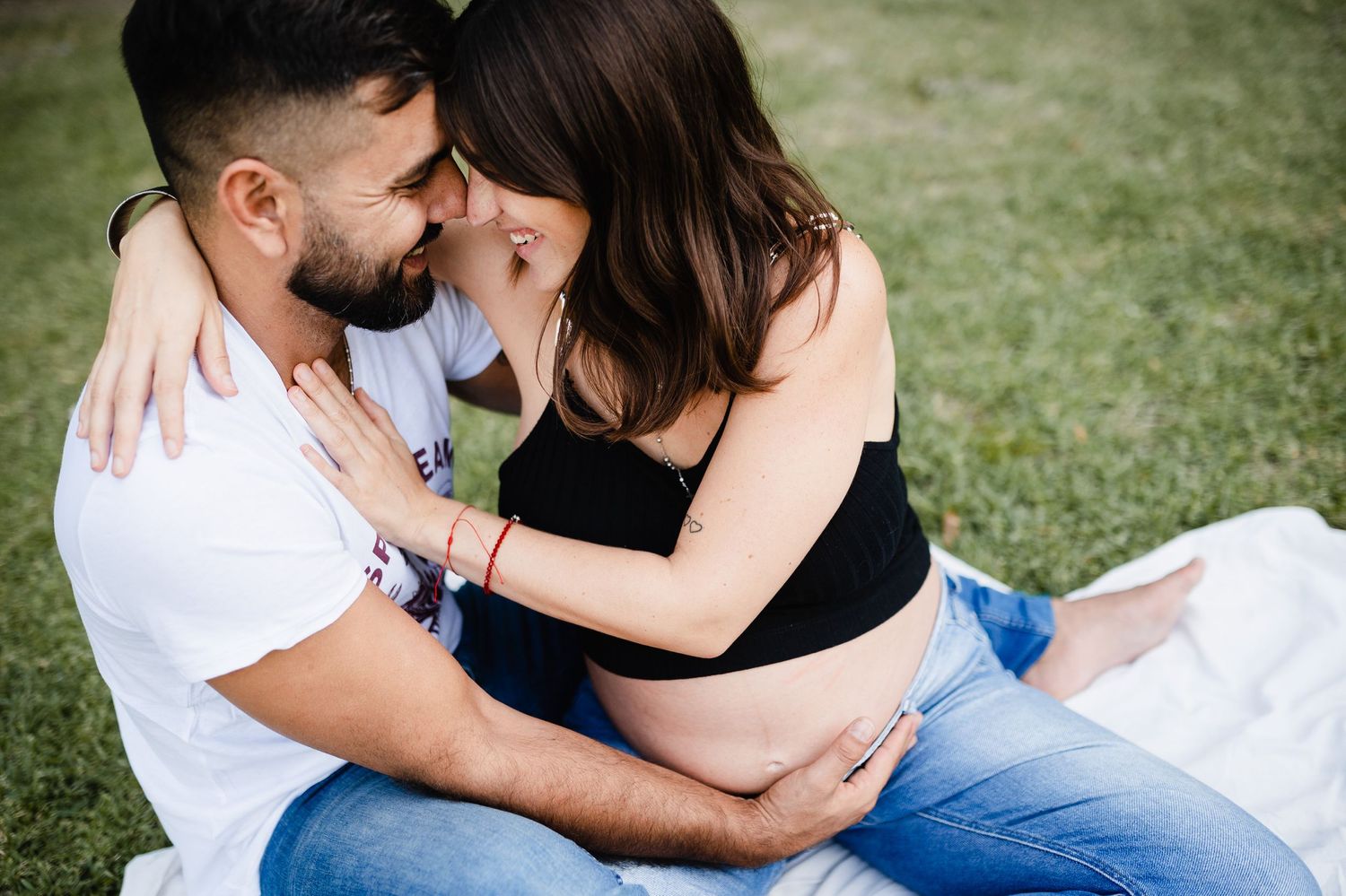 Intimate moment captured on lawn during maternity photoshoot.