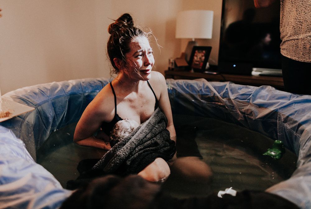 Birthing person crying holding her newborn baby