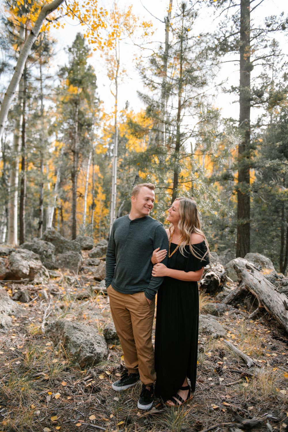 Couple sharing a joyful moment among golden aspen trees in rocky mountain forest.