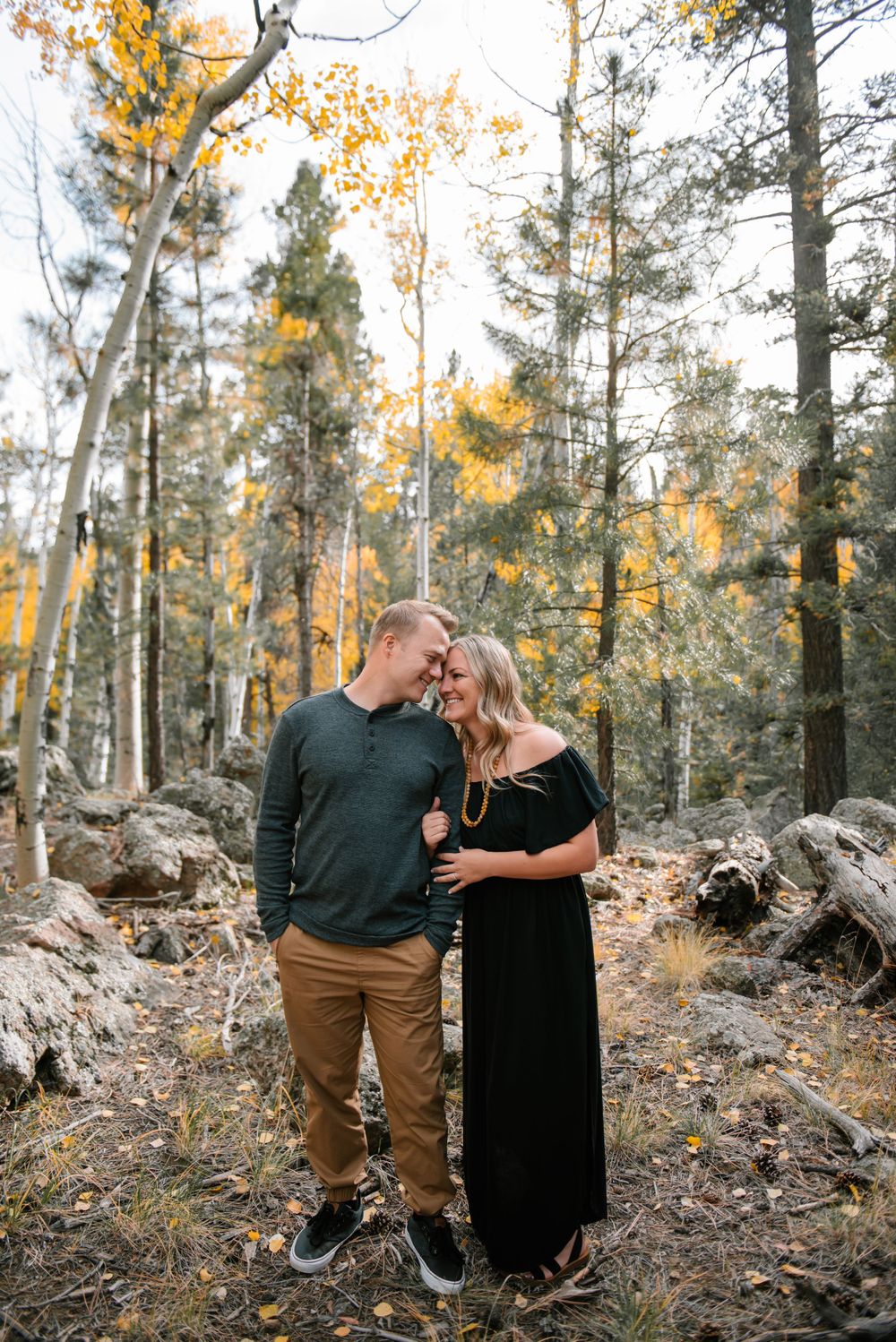 Romantic autumn forest scene with couple embracing among golden aspen trees.