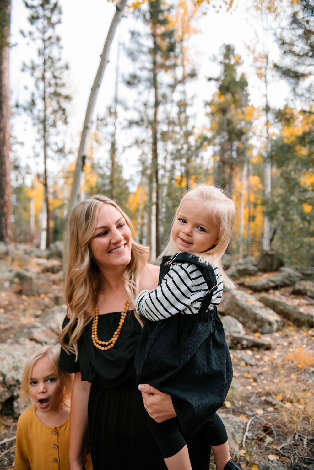 Family moment captured in a forest with golden autumn aspens and rocky terrain.