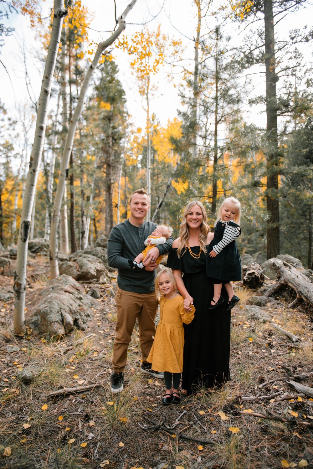 Family portrait among aspen trees with golden fall foliage in mountain setting.