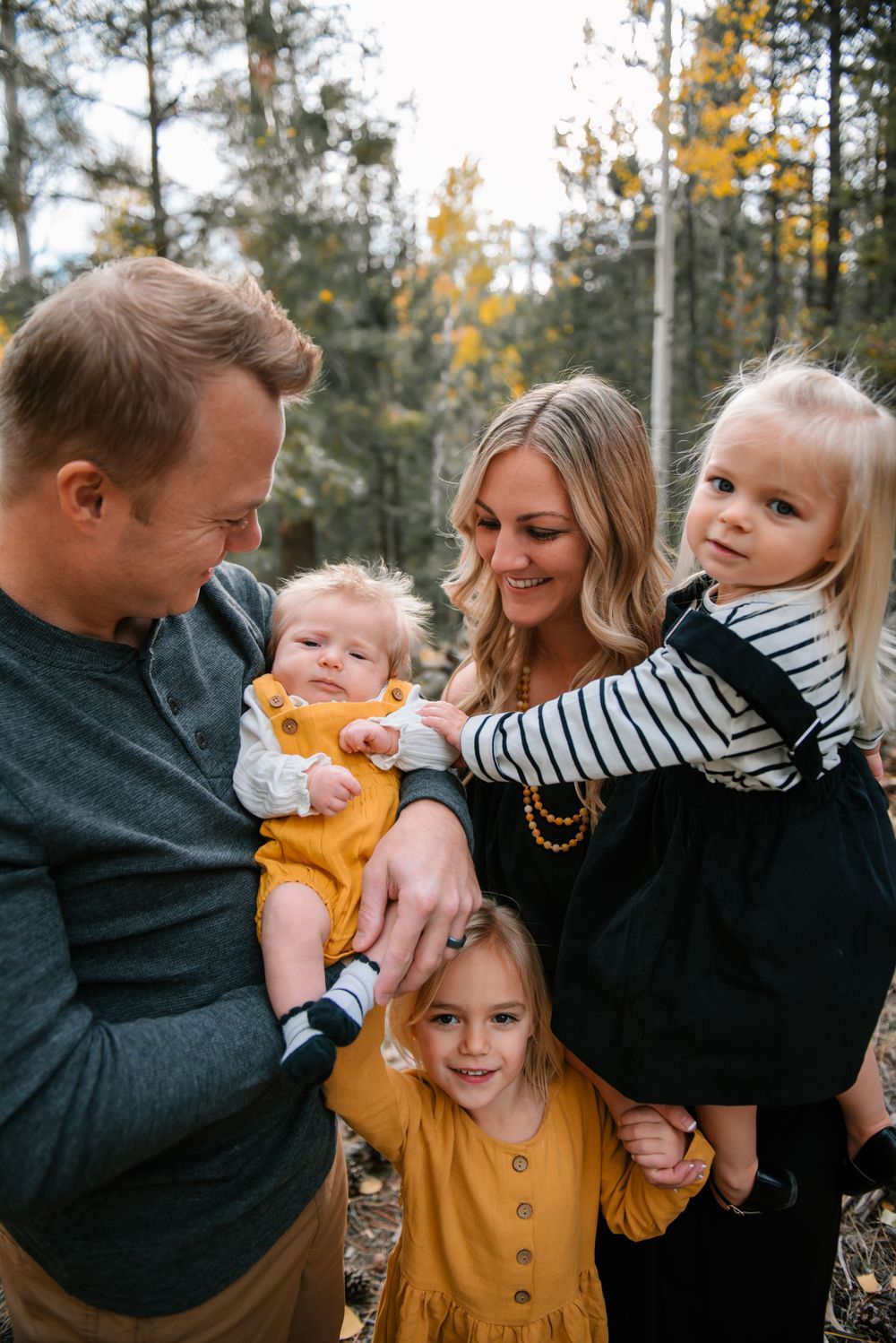 Candid family moment captured on a fall day with everyone wearing coordinating black and mustard outfits.