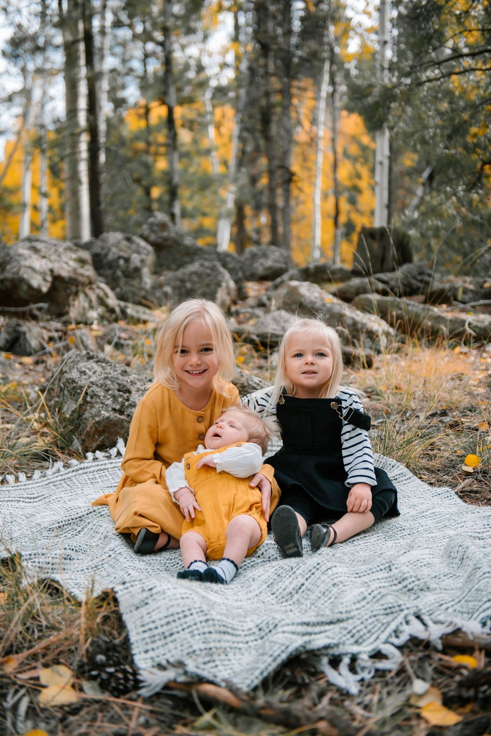 Sweet family photo session on a knit blanket surrounded by fall colors and rocky terrain.