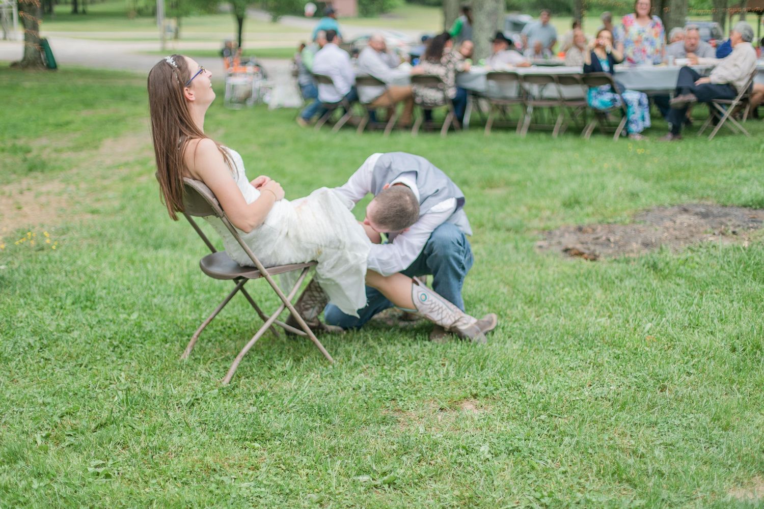 Wedding guests relax in chairs on lawn during outdoor reception celebration.