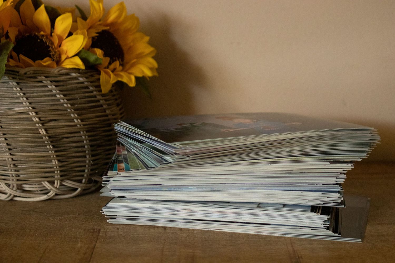 a stack of pictures sitting on a table next to a vase of sunflowers