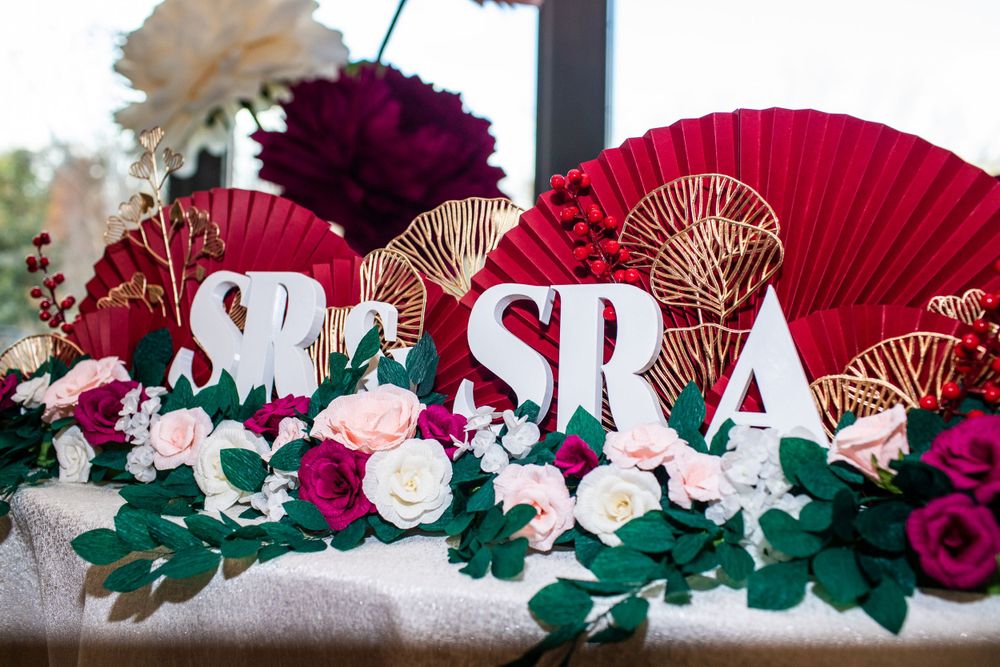 Decorative red fans and floral arrangements with roses create an elegant wedding display.