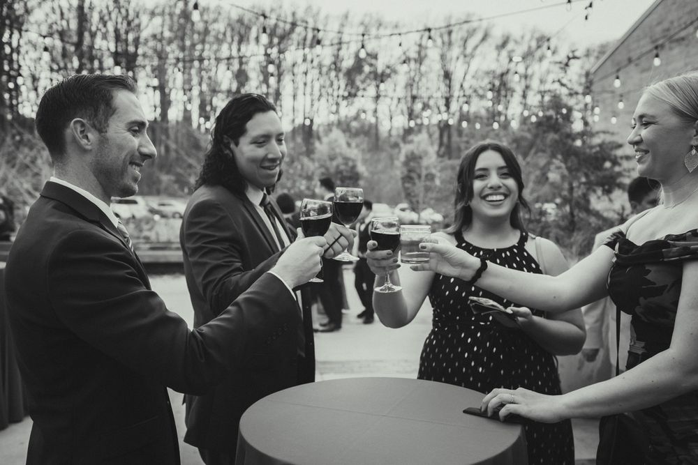 Wedding guests toasting a drink during cocktail hour at Brookside Gardens Visitor's Center South Terrace.