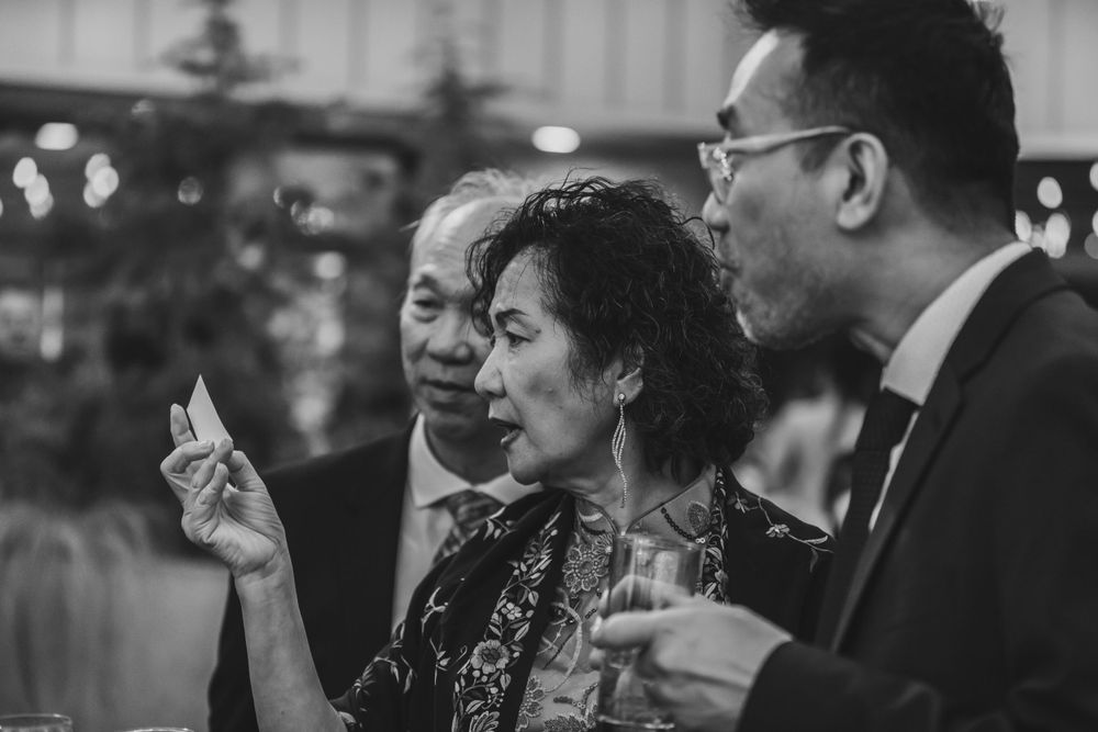 Black and white candid shot of wedding guests sharing stories at reception.