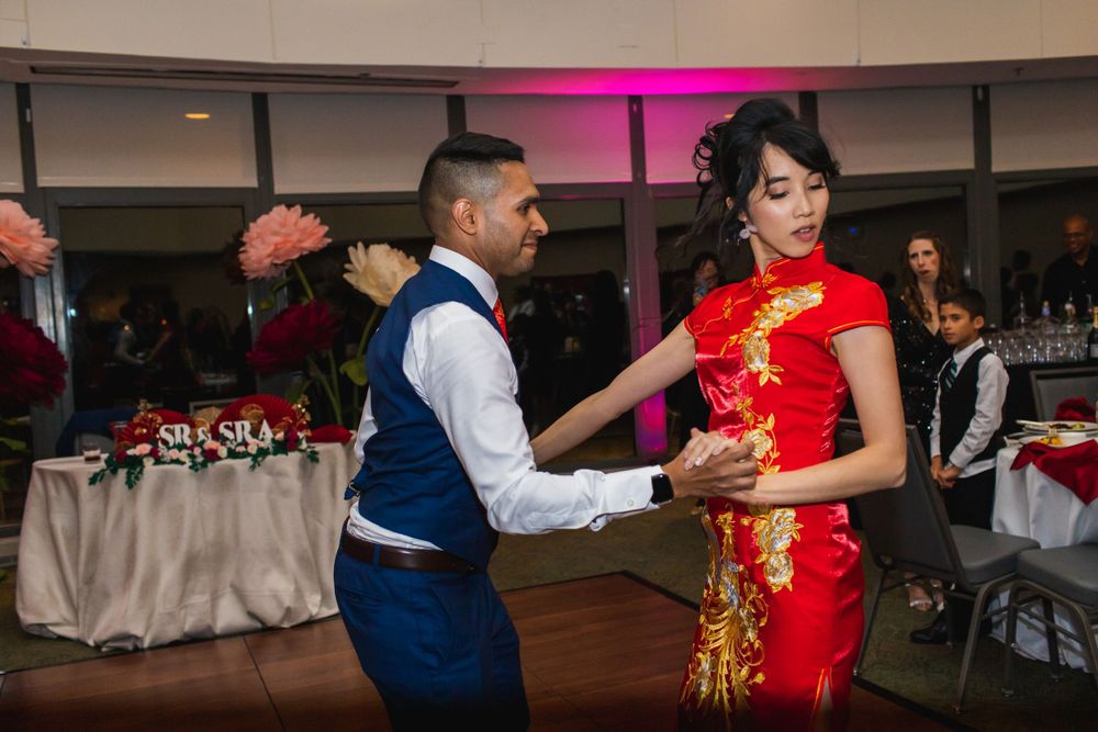 A couple dances together at their reception, with the bride wearing a traditional red qipao dress.