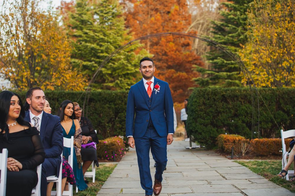 Wedding ceremony walking processional in outdoor garden with beautiful fall foliage.
