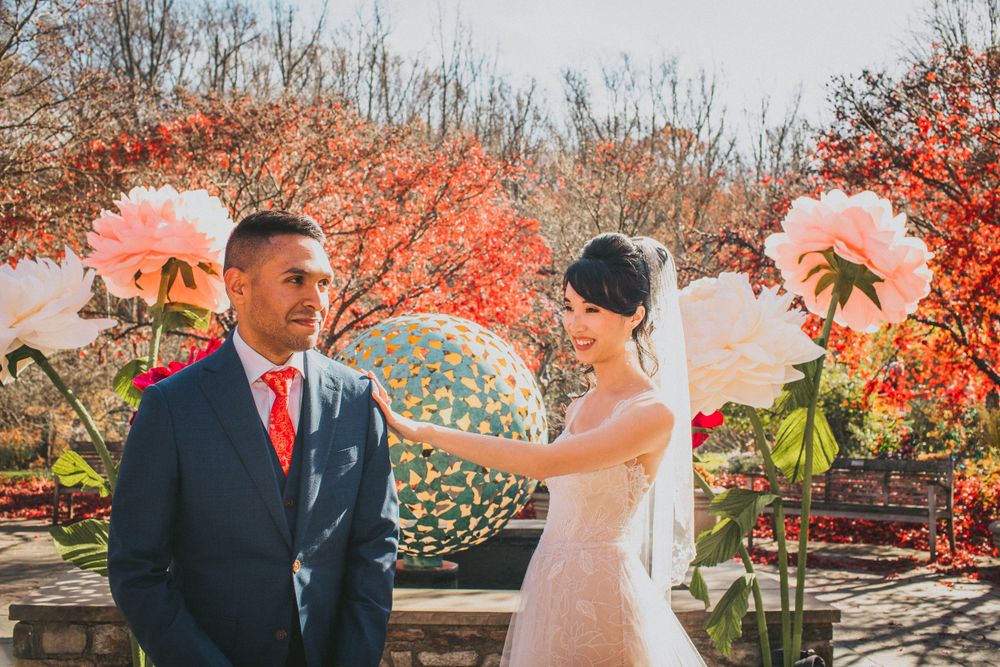 Brookside Gardens wedding with fall foliage. Bride taps on groom's shoulder for first look moment.
