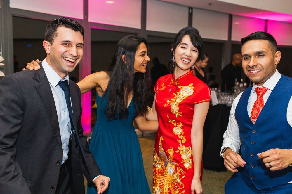 Wedding guests socializing and enjoying themselves at a reception with pink lighting.