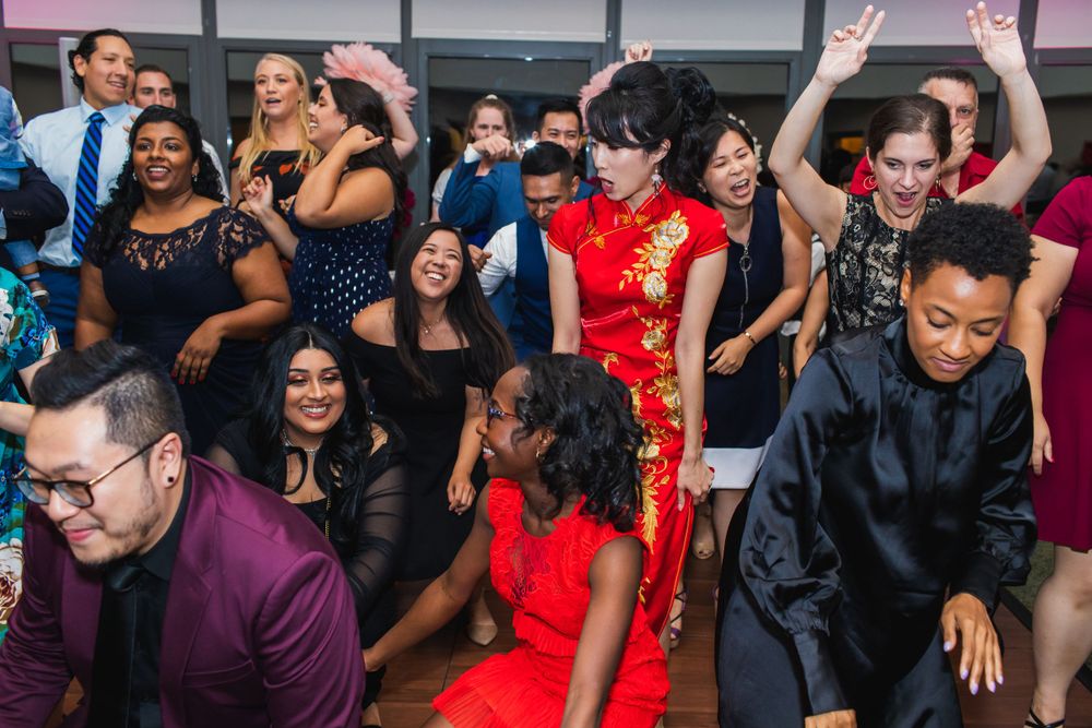 Wedding guests dancing and celebrating on a red-lit dance floor.