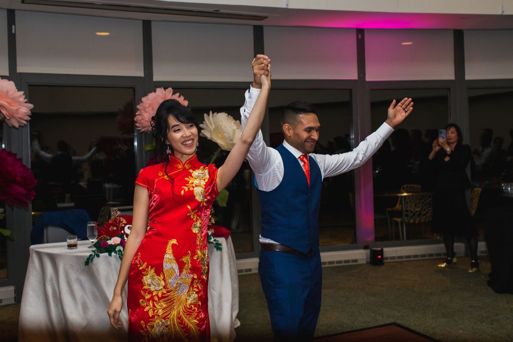 A couple makes their grand entrance at a wedding reception wearing traditional red and blue attire.