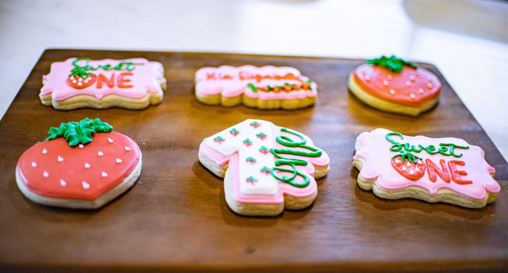 Decorated sugar cookies with pink frosting arranged on a wooden surface.