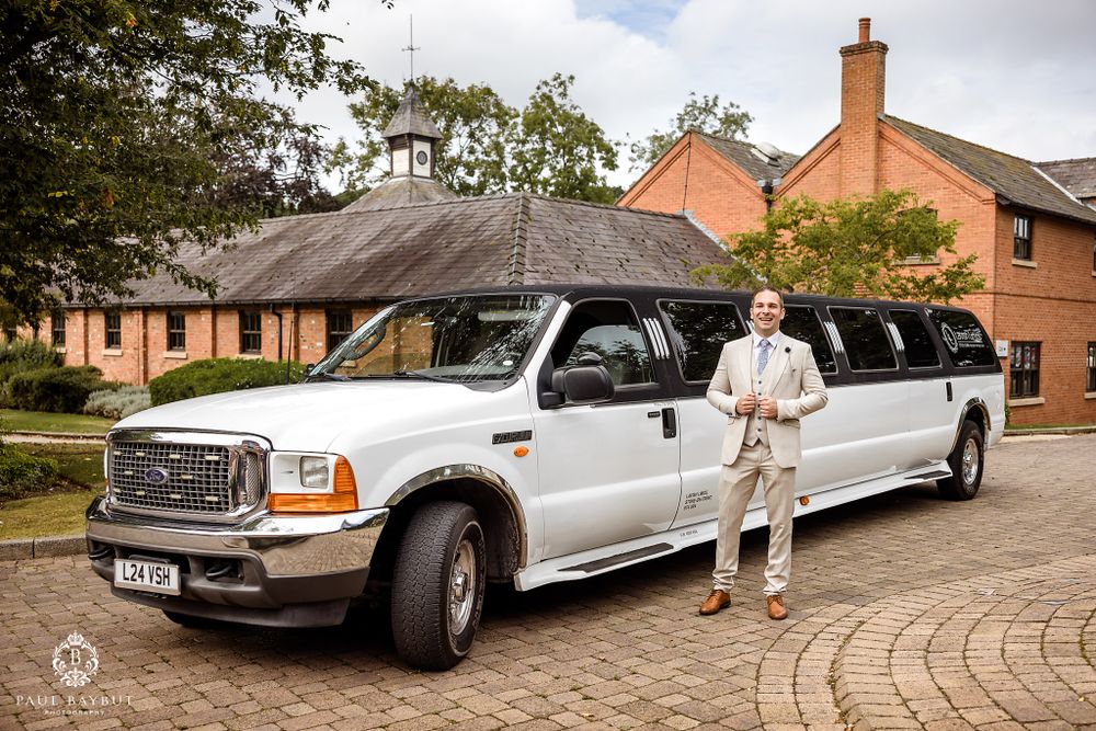 White stretch limousine parked outside brick buildings for a wedding celebration.