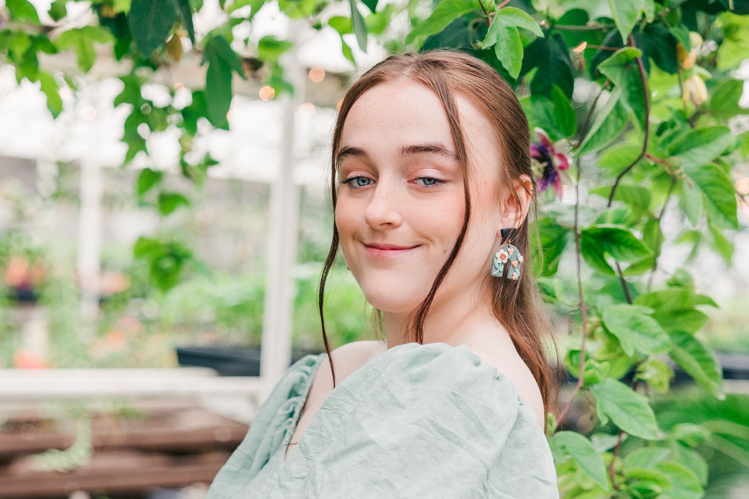 Close-up garden portrait in vintage-inspired sage dress with natural lighting.