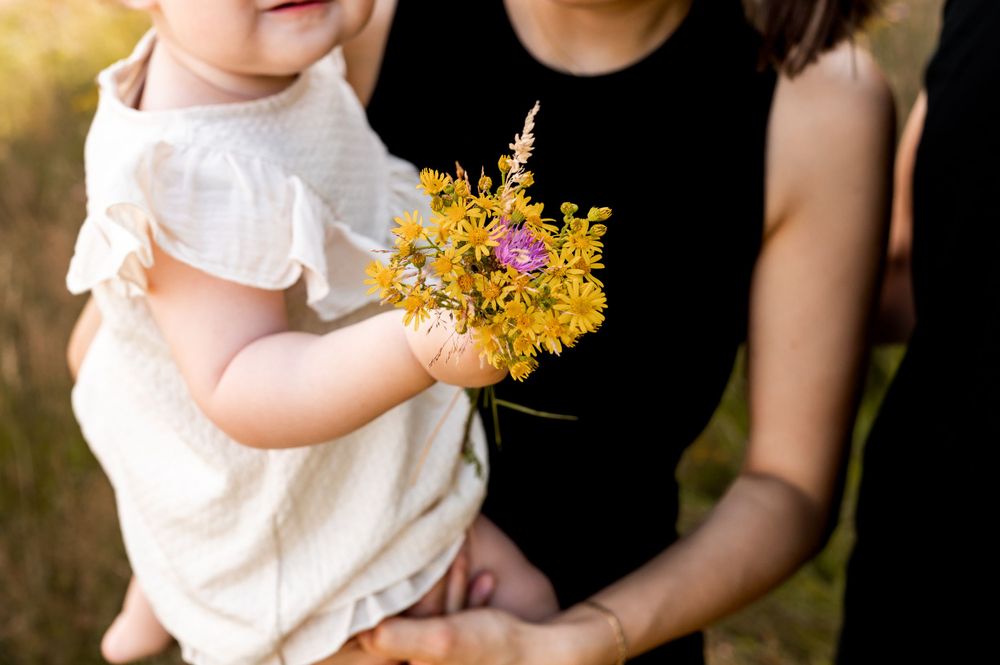 Leuke detailfoto tijdens een gezinsshoot met een dochter van één jaar met bloemen in haar handen