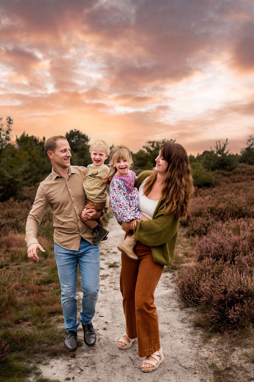 Gezin van vier met een dochter en een zoon met een dramatische zonsondergang op de achtergrond in de bloeiende heide