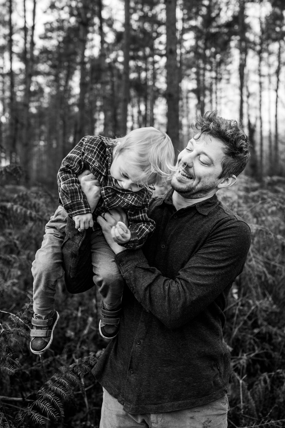 Speelse foto van papa en zoon, bewerkt in zwart-wit, gemaakt in de bossen van Averbode