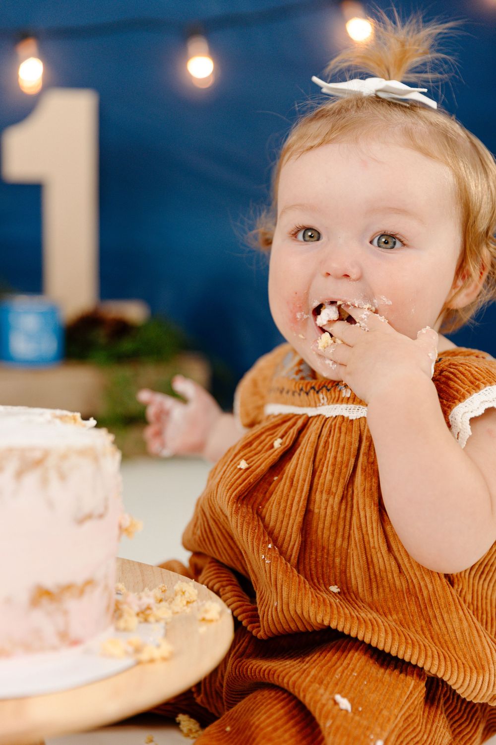 A baby girl eating cake during her cake smash