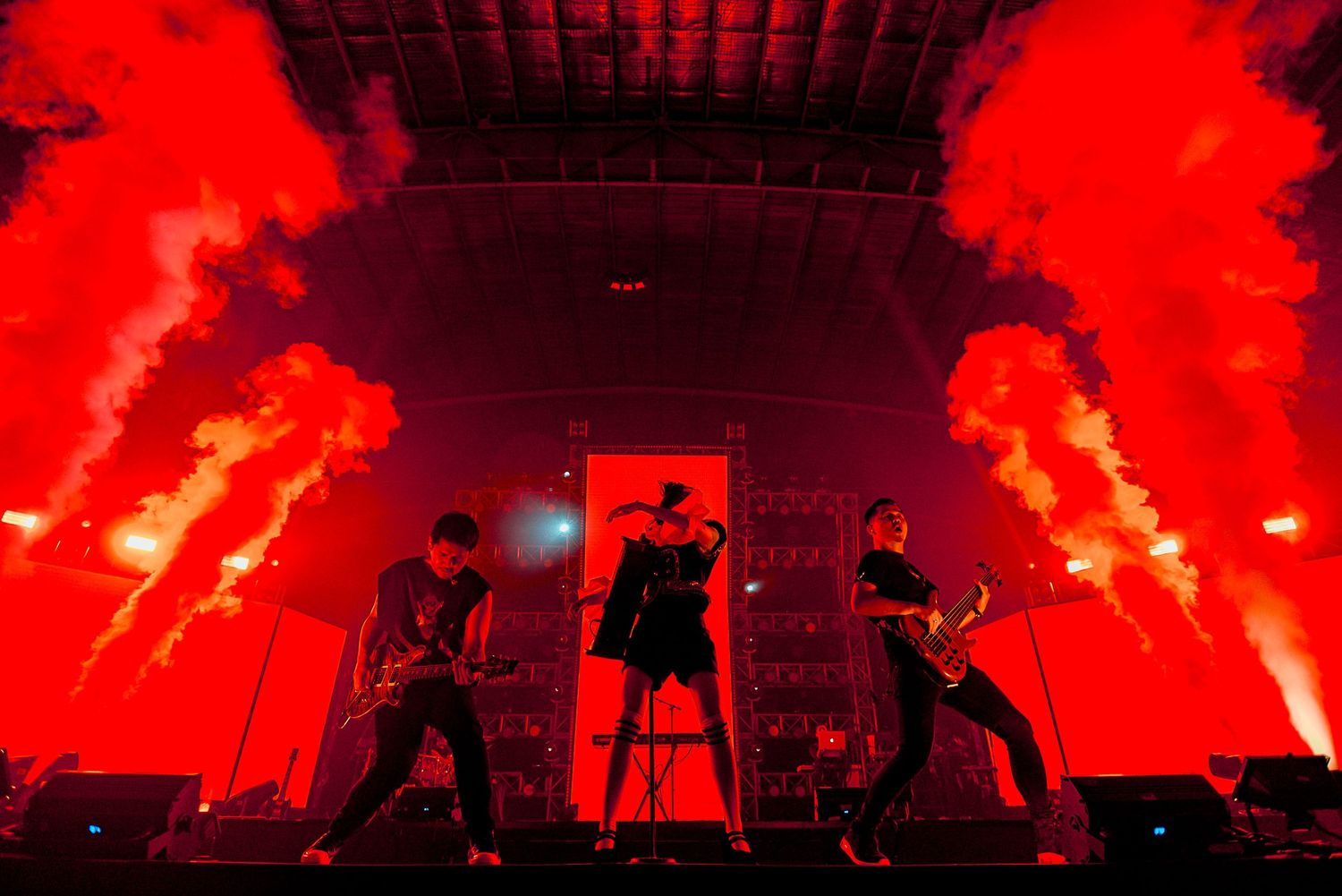 Rock band performs on stage with dramatic red pyrotechnics effects.