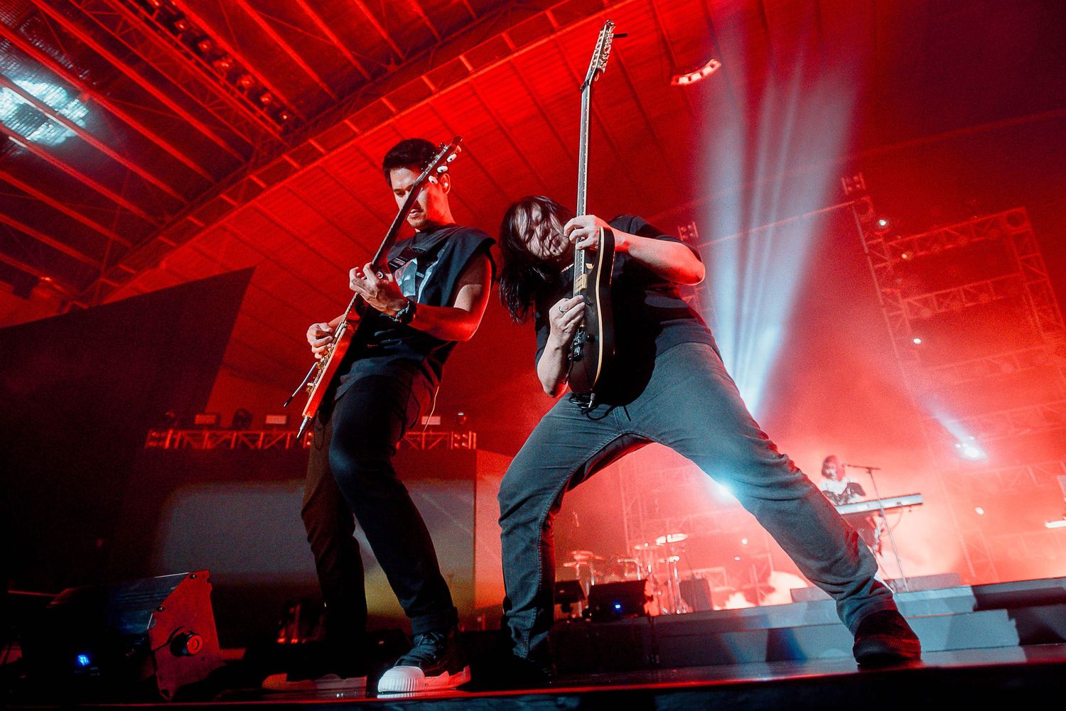 Dynamic concert performance with musicians in dramatic poses under red stage lighting.