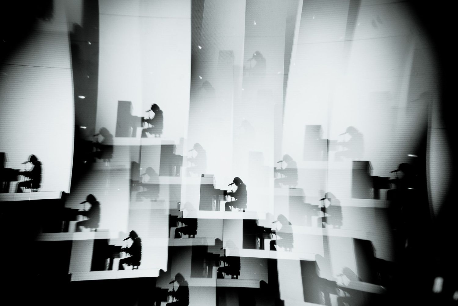 Abstract multiple exposure of performers in geometric white spaces.