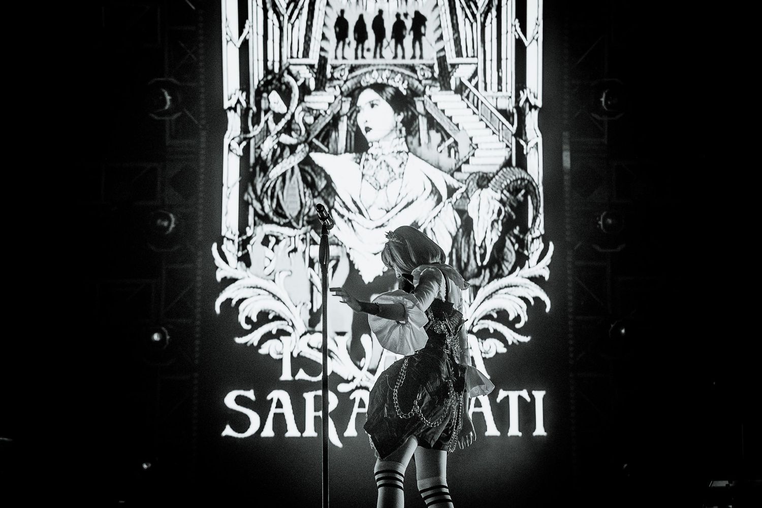 Black and white gothic-style concert backdrop featuring artistic medieval imagery.