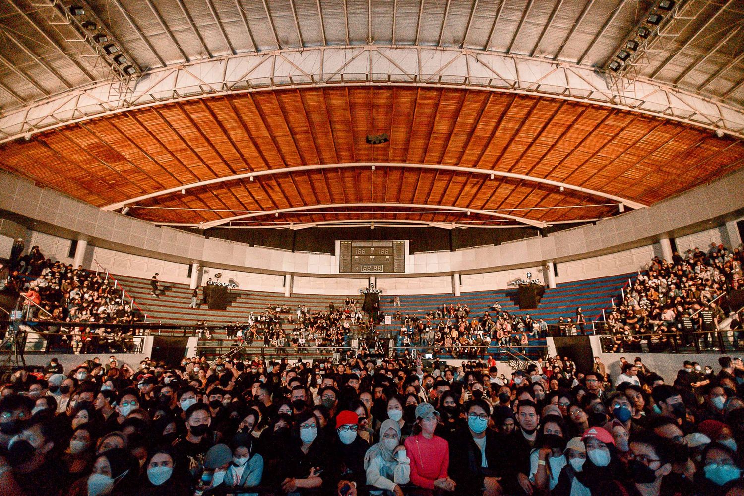 Large indoor arena filled with spectators under a curved wooden ceiling during a performance event.