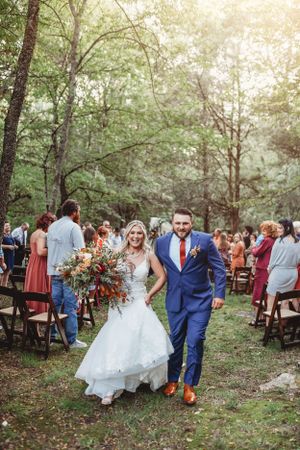 Outdoor forest wedding reception with bride and groom walking among guests.