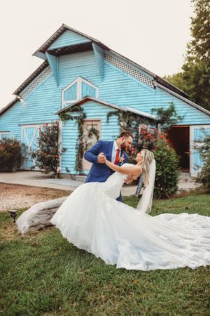 A romantic wedding photo series showing a couple dipping and posing in front of a light blue house.