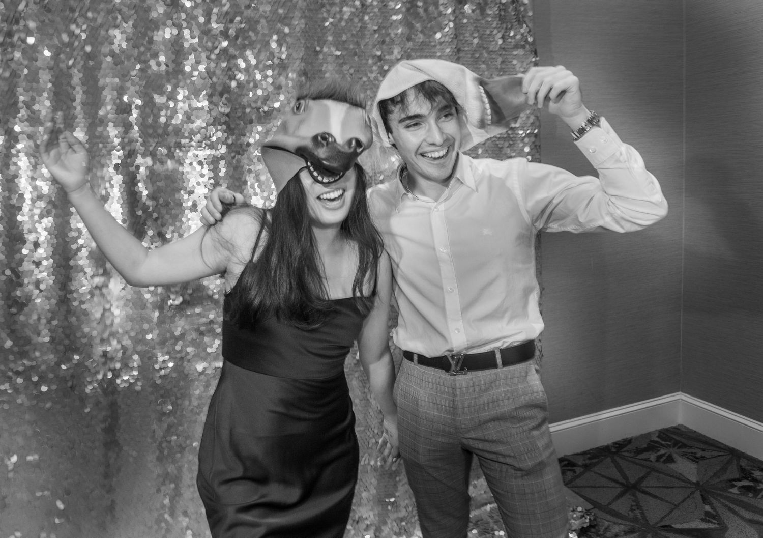 Black and white photo of party guests posing with props against a sparkly backdrop.