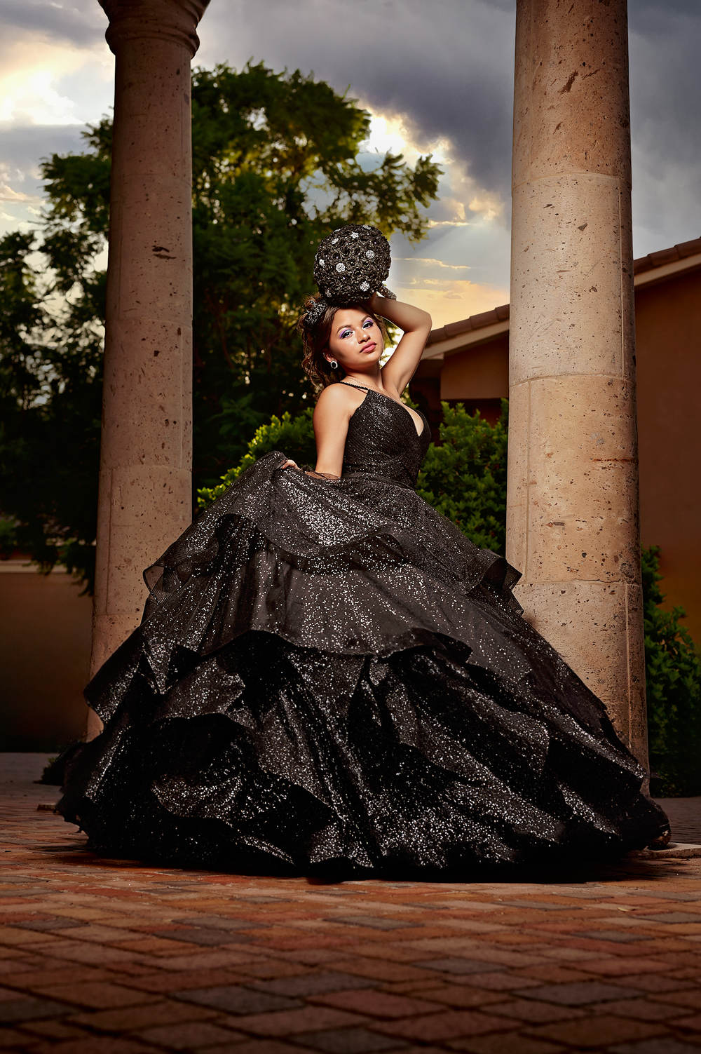 Dramatic black ballgown photoshoot between classical columns during golden hour.