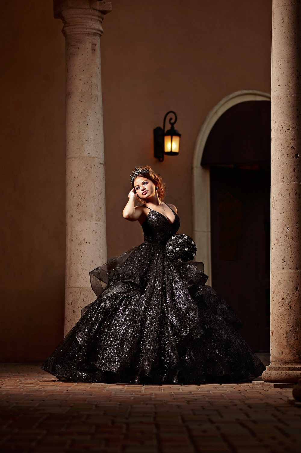 Elegant evening portrait in a sparkly black ballgown against architectural columns.